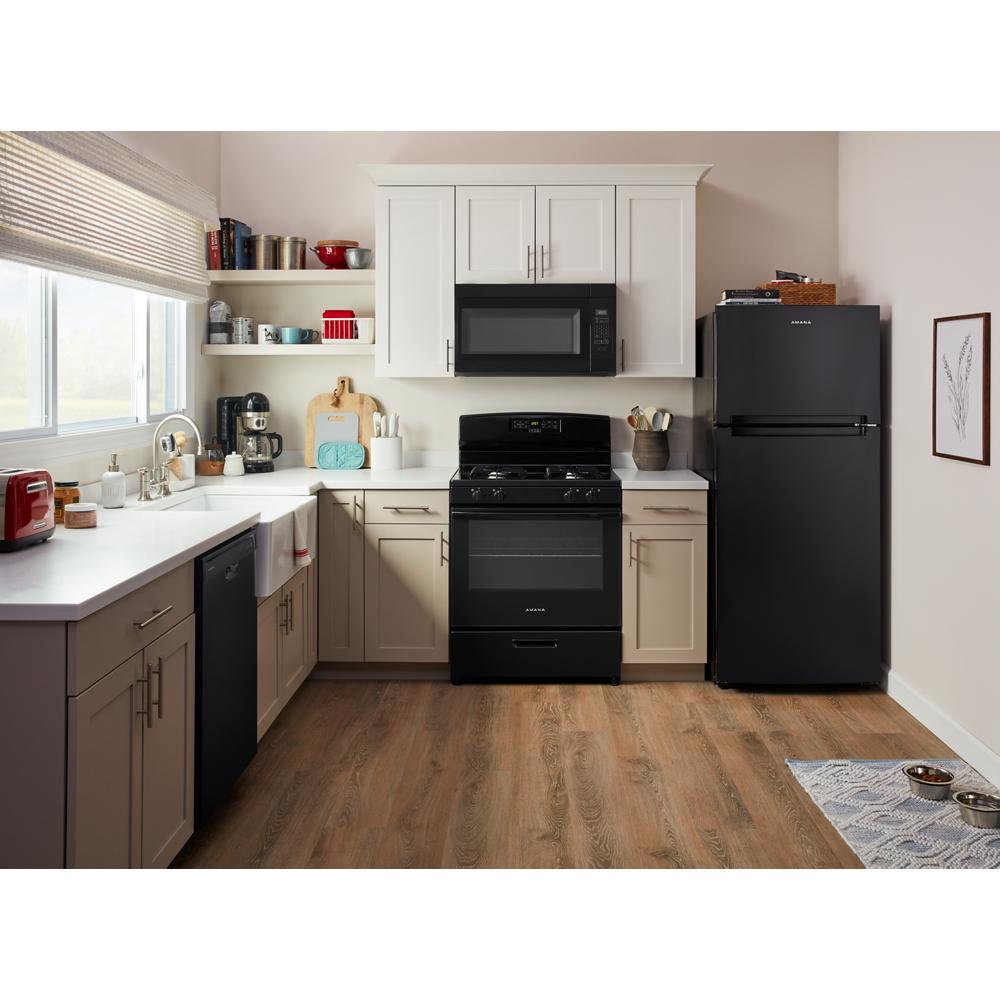 Modern kitchen with black over-the-range microwave, matching stove, and refrigerator against neutral cabinetry and wood floor.