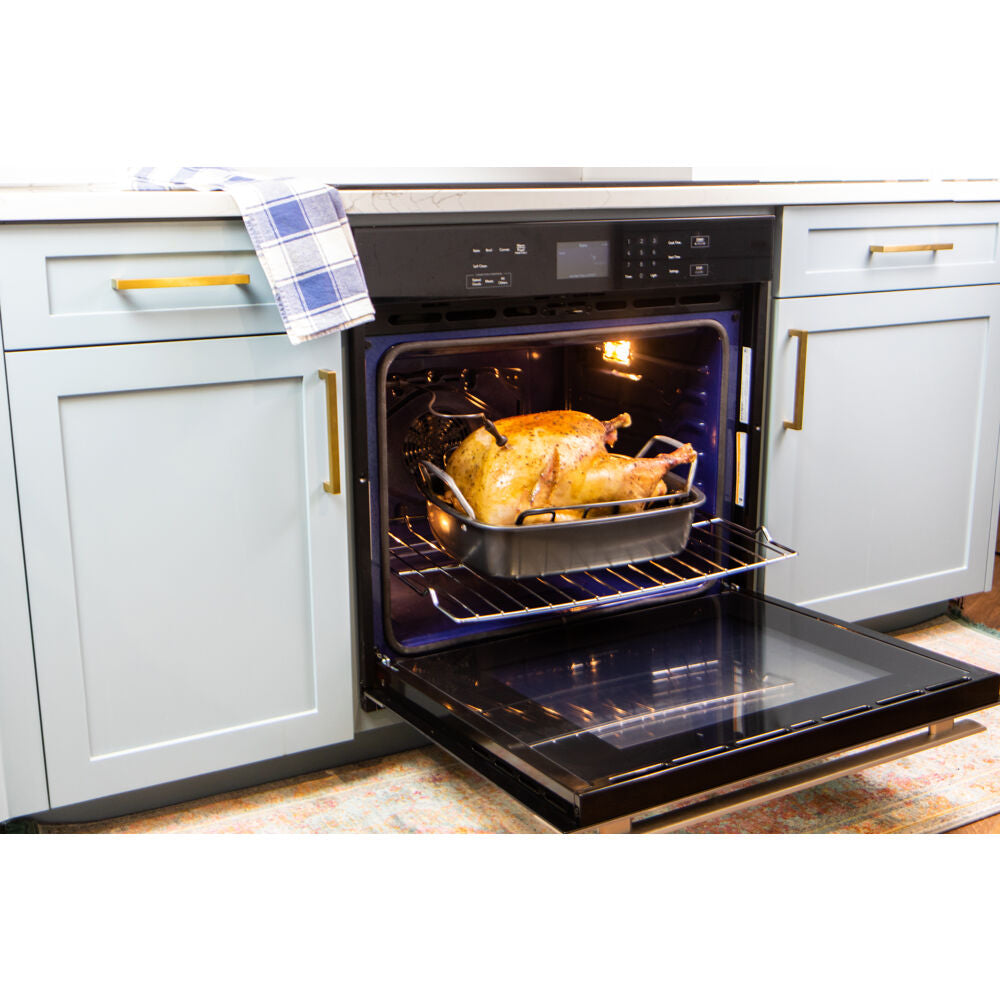 Open built-in electric wall oven with black glass front and stainless steel trim cooking a roasted chicken inside kitchen setting