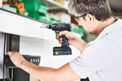 Person tightening screws with a Festool cordless drill for home improvement in a bright workshop setting