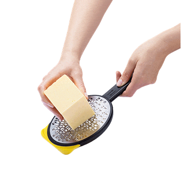 Hand grating block of cheese using yellow medium two-sided speed grater for kitchenware and kitchen gadgets under $50 collections