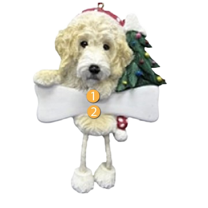 Cream-colored Labradoodle dog ornament with dangling legs holding a blank sign and decorated Christmas tree
