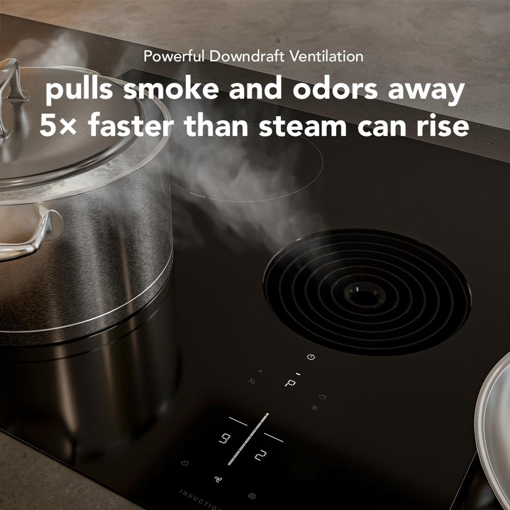 Close-up of black induction cooktop with downdraft vent actively pulling steam from large stainless steel pot on kitchen counter