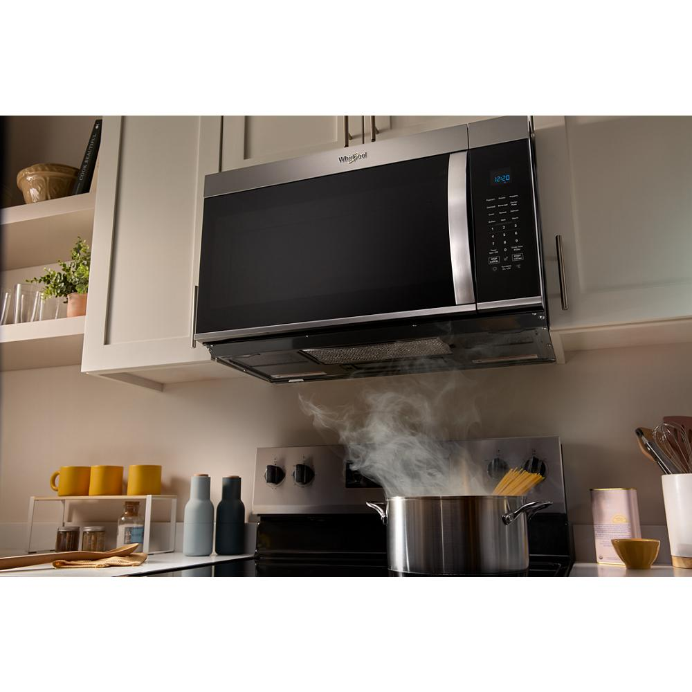 Stainless steel over the range microwave installed above stovetop with steaming pot cooking in modern kitchen