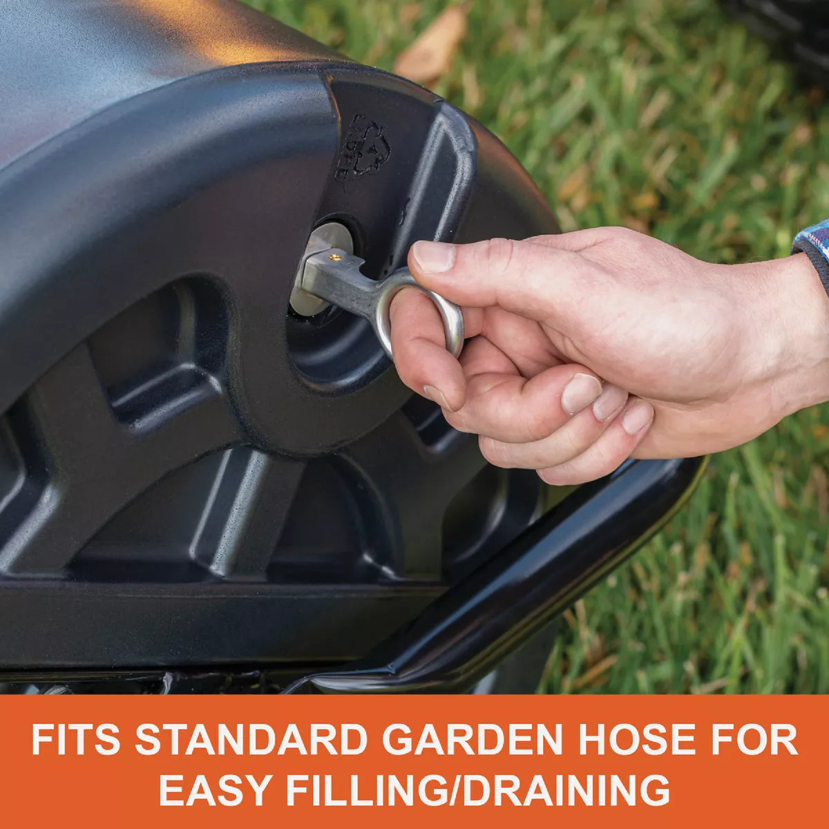 Hand inserting key into black polyethylene roller valve, showing hose connection for filling and draining lawn tool
