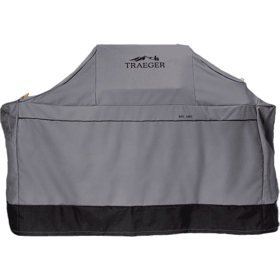 Gray heavy-duty polyester grill cover with black trim, designed for outdoor grilling protection in Traeger accessories collection