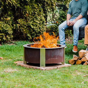 Round corten steel smokeless fire pit with active flames, designed for outdoor living and patio furniture collections