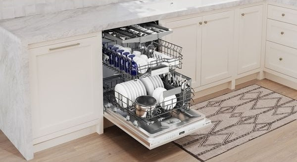 Open 24-inch custom panel ready dishwasher with neatly arranged white dishes and cookware inside in modern kitchen