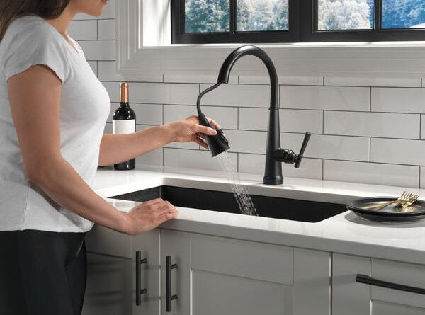 Matte black pull-down kitchen faucet with single handle and touch activation in modern white countertop sink setting