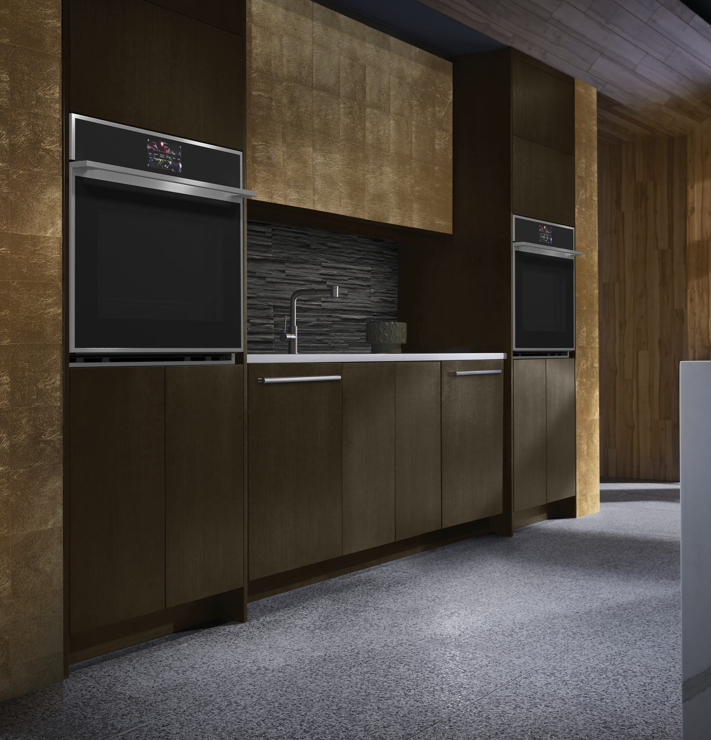 Contemporary kitchen featuring two minimalist single wall ovens set in dark cabinetry with textured gold walls and stone backsplash