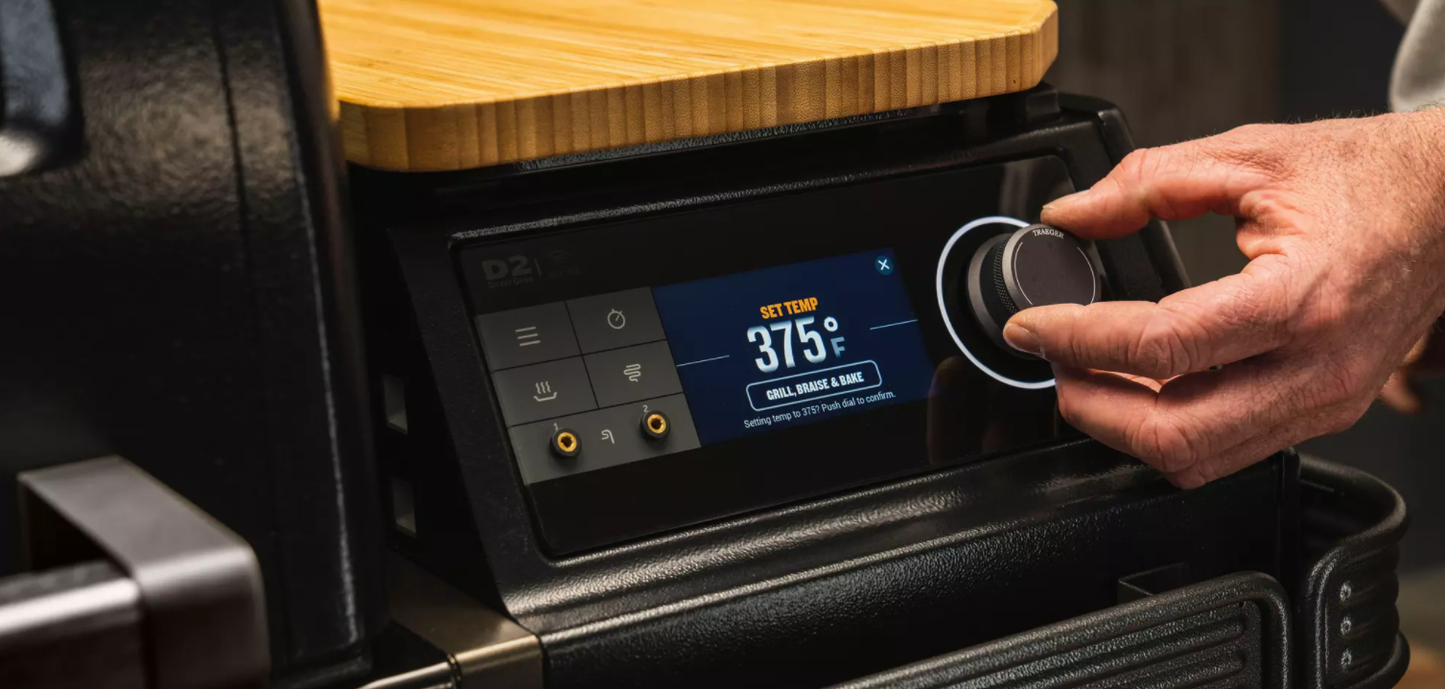 Close-up of hand adjusting digital temperature control on premium wood pellet grill for outdoor cooking and grilling
