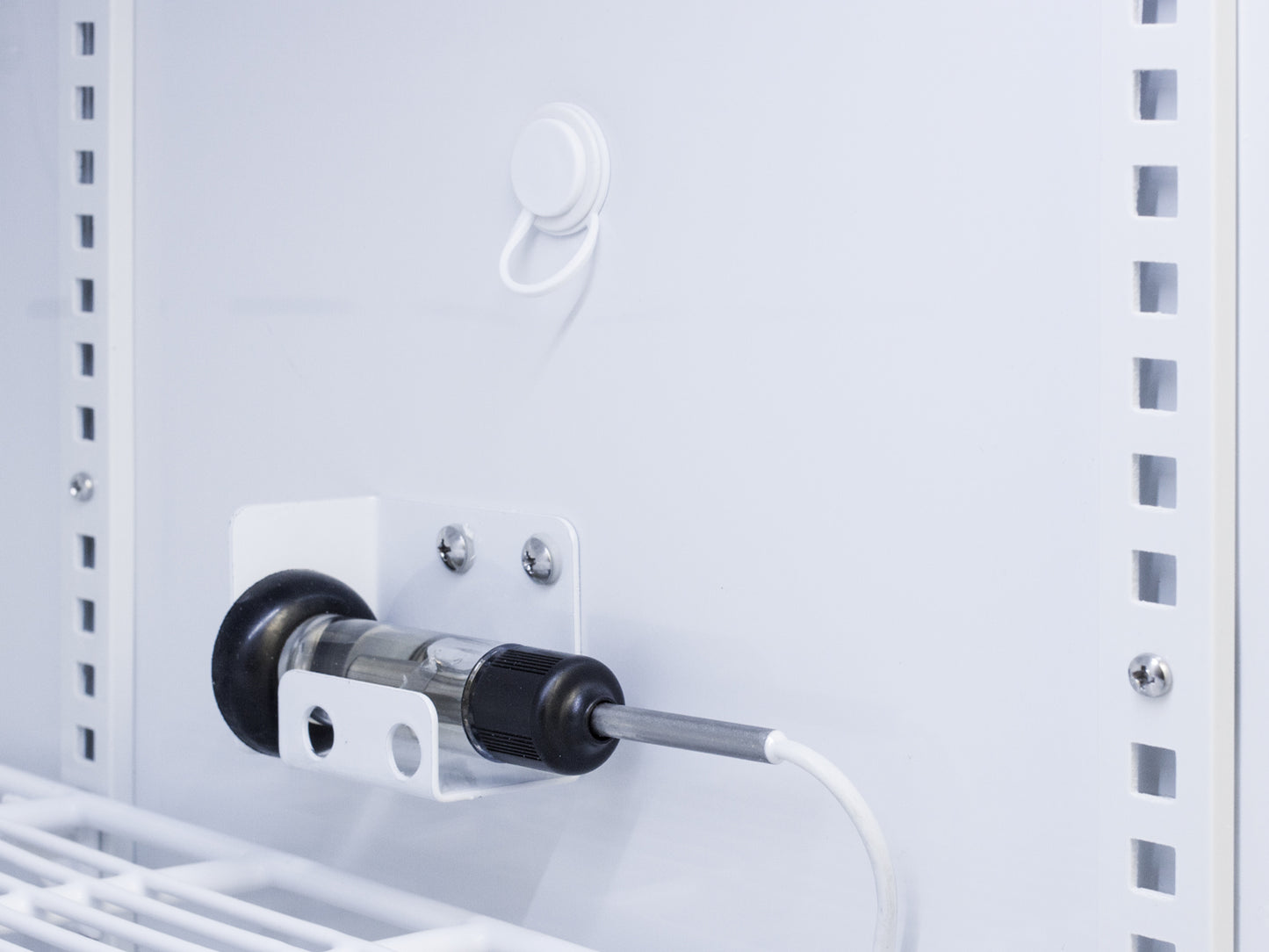 Close-up of sensor probe mounted inside white interior of upright refrigerator in appliances and kitchenware collection