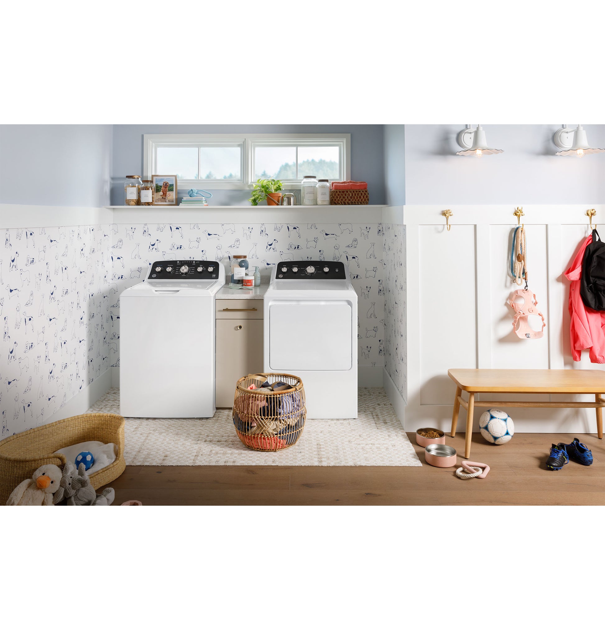 Laundry room with white top load washer and matching gas dryer, laundry basket, and children's shoes in an appliances setting