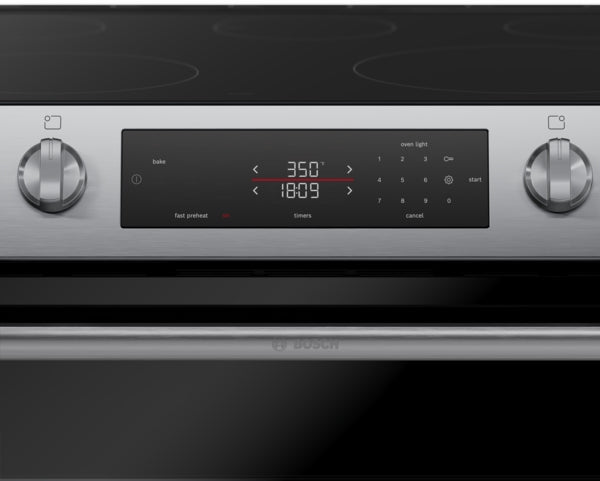 Close-up of stainless steel electric freestanding range control panel with digital display and rotary knobs