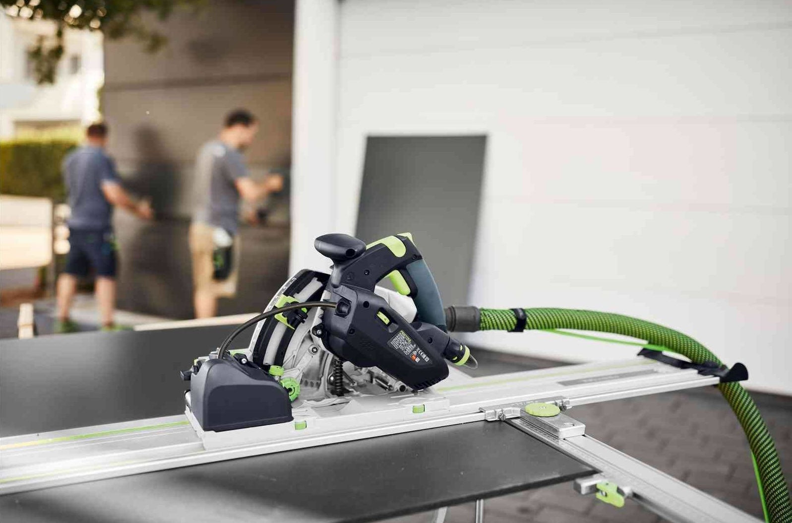 Festool plunge cut track saw on guide rail with vacuum hose in workshop setting for precision woodworking tools.