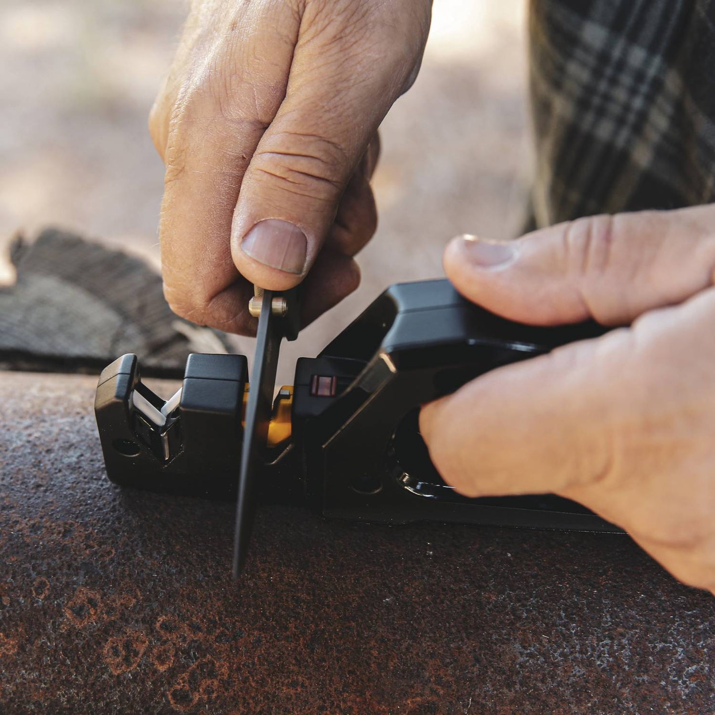 Hands sharpening blade using black Work Sharp Pivot Pro for kitchen gadgets in outdoor home tool maintenance setting