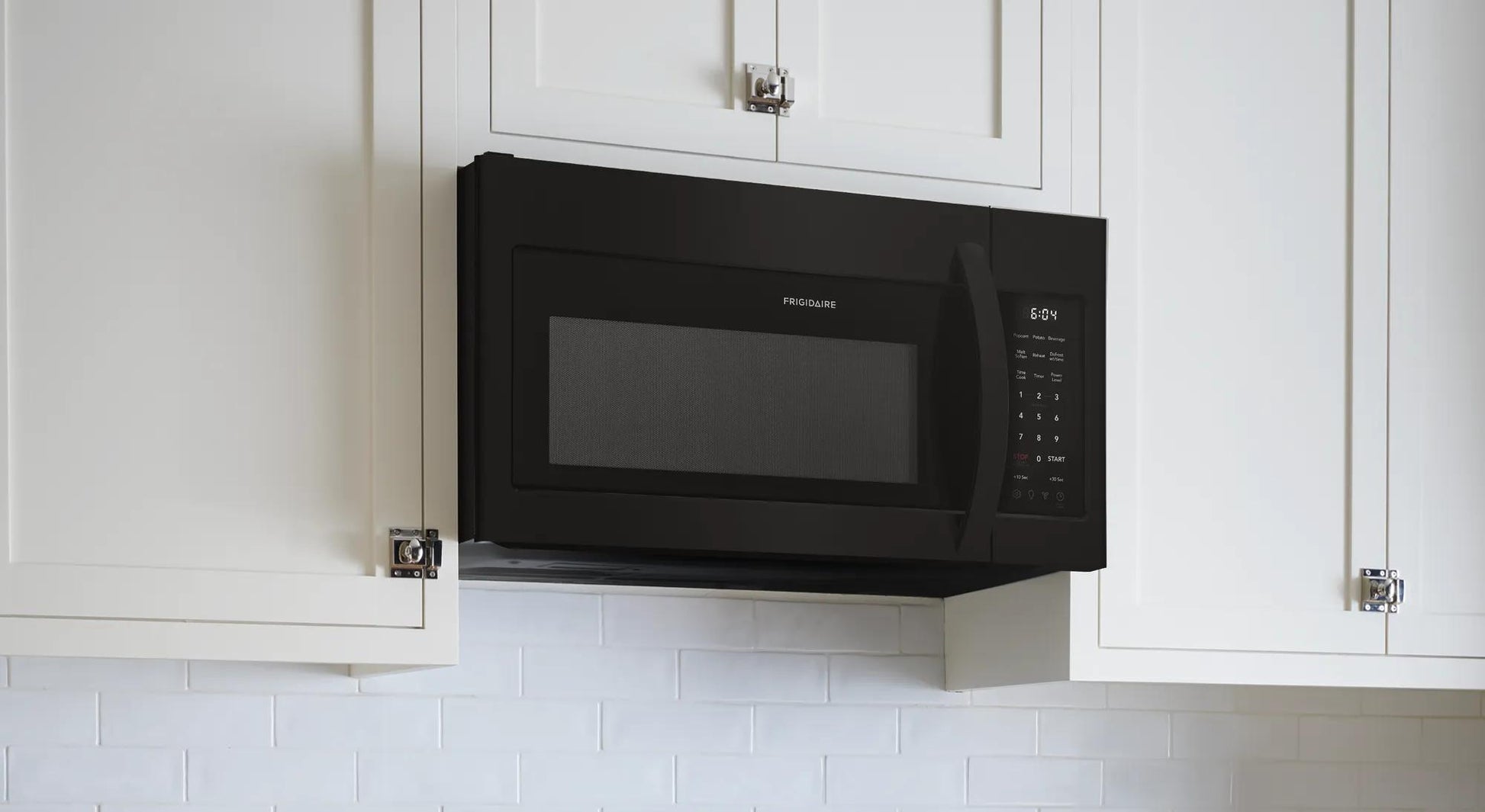 Black over-the-range microwave with digital control panel mounted above white kitchen cabinets in modern kitchen setup