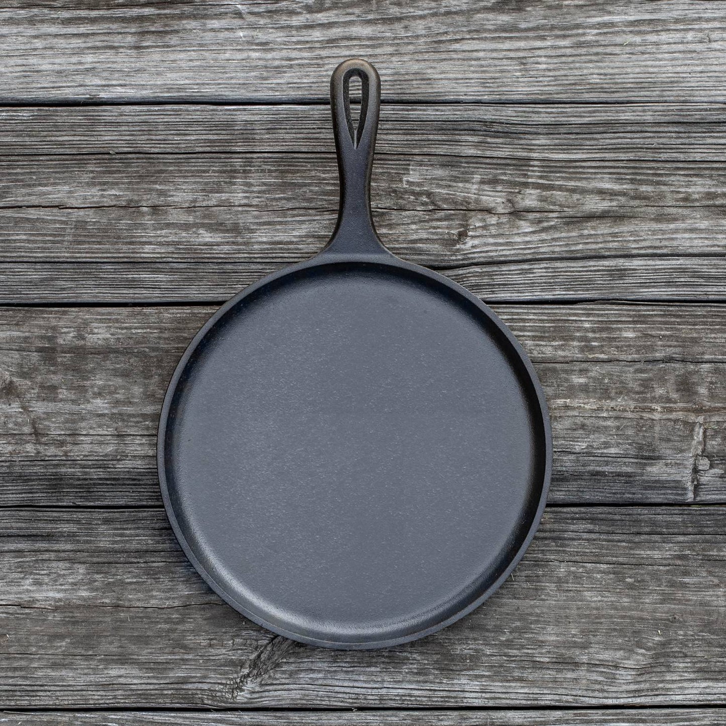 Round cast iron griddle with handle, ideal for grilling and cooking in kitchenware and outdoor living collections under $50