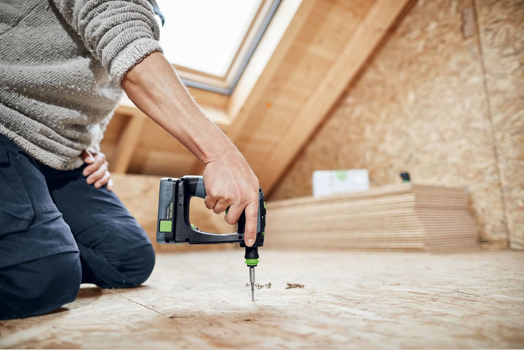 Person using compact cordless drill to drive screws into wooden surface during woodworking project