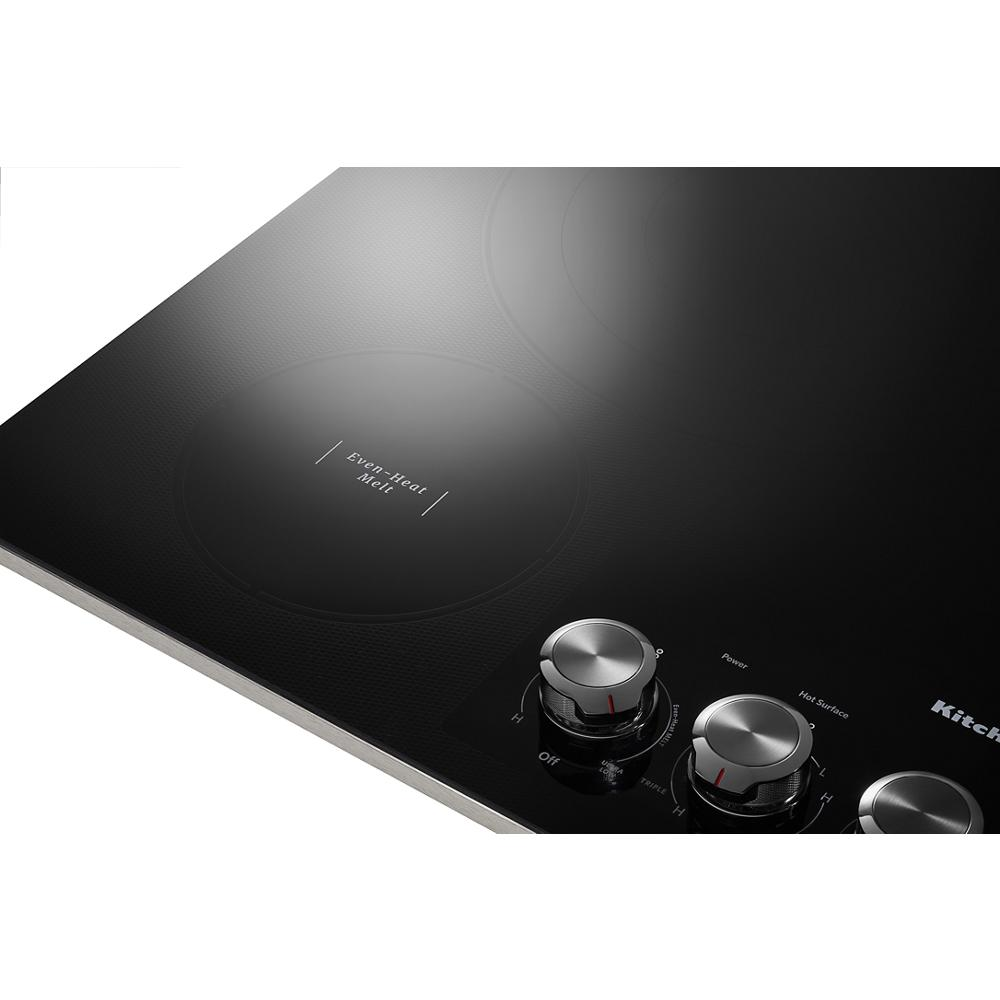 Close-up of black electric cooktop with radiant heating element and stainless steel knob controls for kitchen appliances.