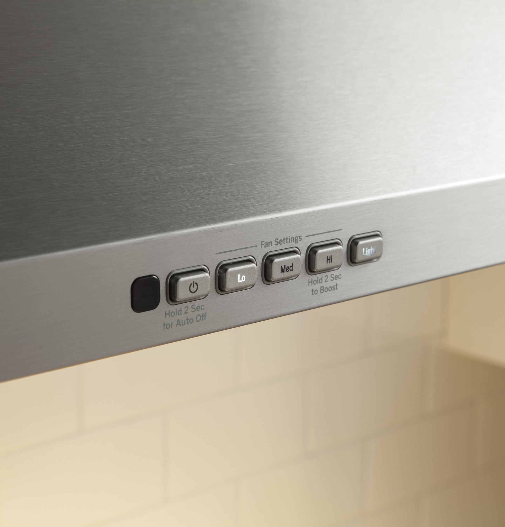 Close-up of control buttons for fan speed and light on stainless steel wall-mount range hood in kitchen appliances collection