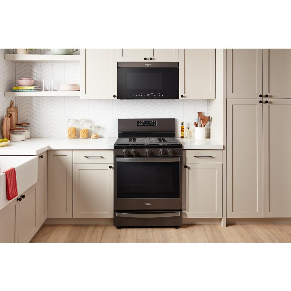 Black built-in over-the-range microwave and freestanding oven in a modern kitchen with neutral cabinetry and light flooring