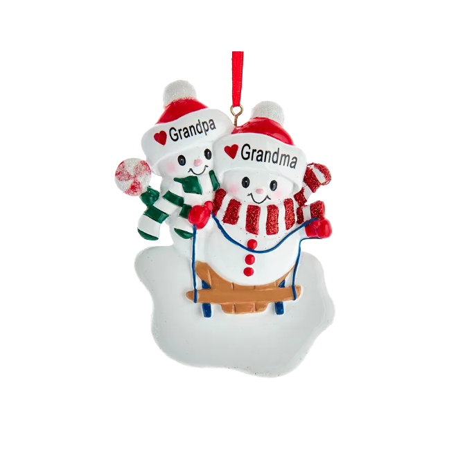Festive Grandma and Grandpa snow couple ornament sledding on snow with red and green winter accessories for Christmas decor
