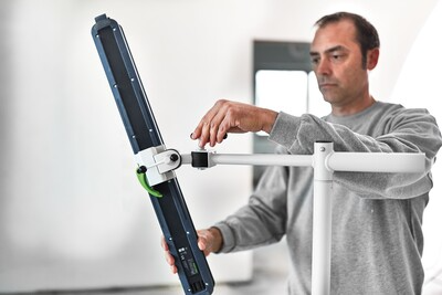 Man positioning adjustable Festool work light on white stand for precise inspection in home improvement tasks