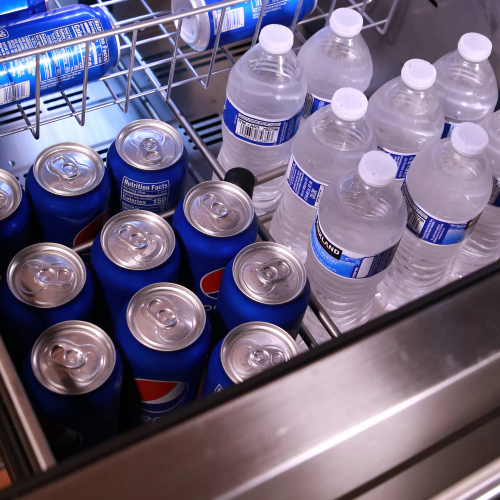Open stainless steel beverage center drawer with canned sodas and bottled water for kitchen appliance collections