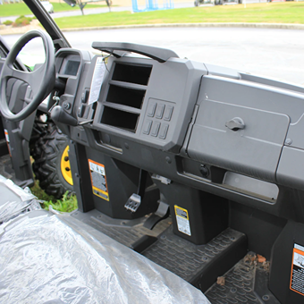 Close-up of utility vehicle interior featuring dashboard storage compartments and durable floor mats for outdoor work tasks
