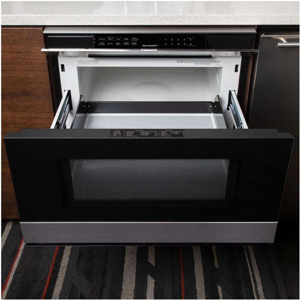 Built-in flat panel microwave drawer with black glass and stainless steel trim in modern kitchen cabinetry installation