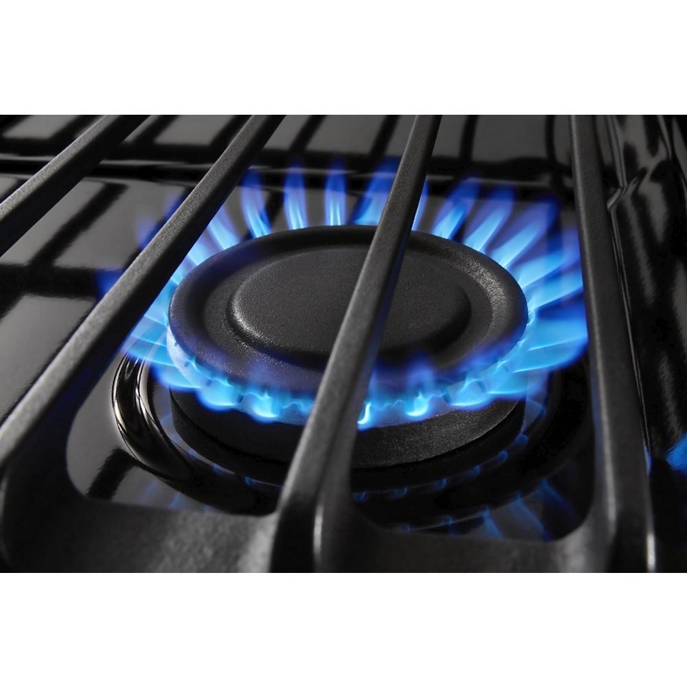 Close-up of lit gas burner with blue flame and cast iron grates on a black Whirlpool range from Ranges collection