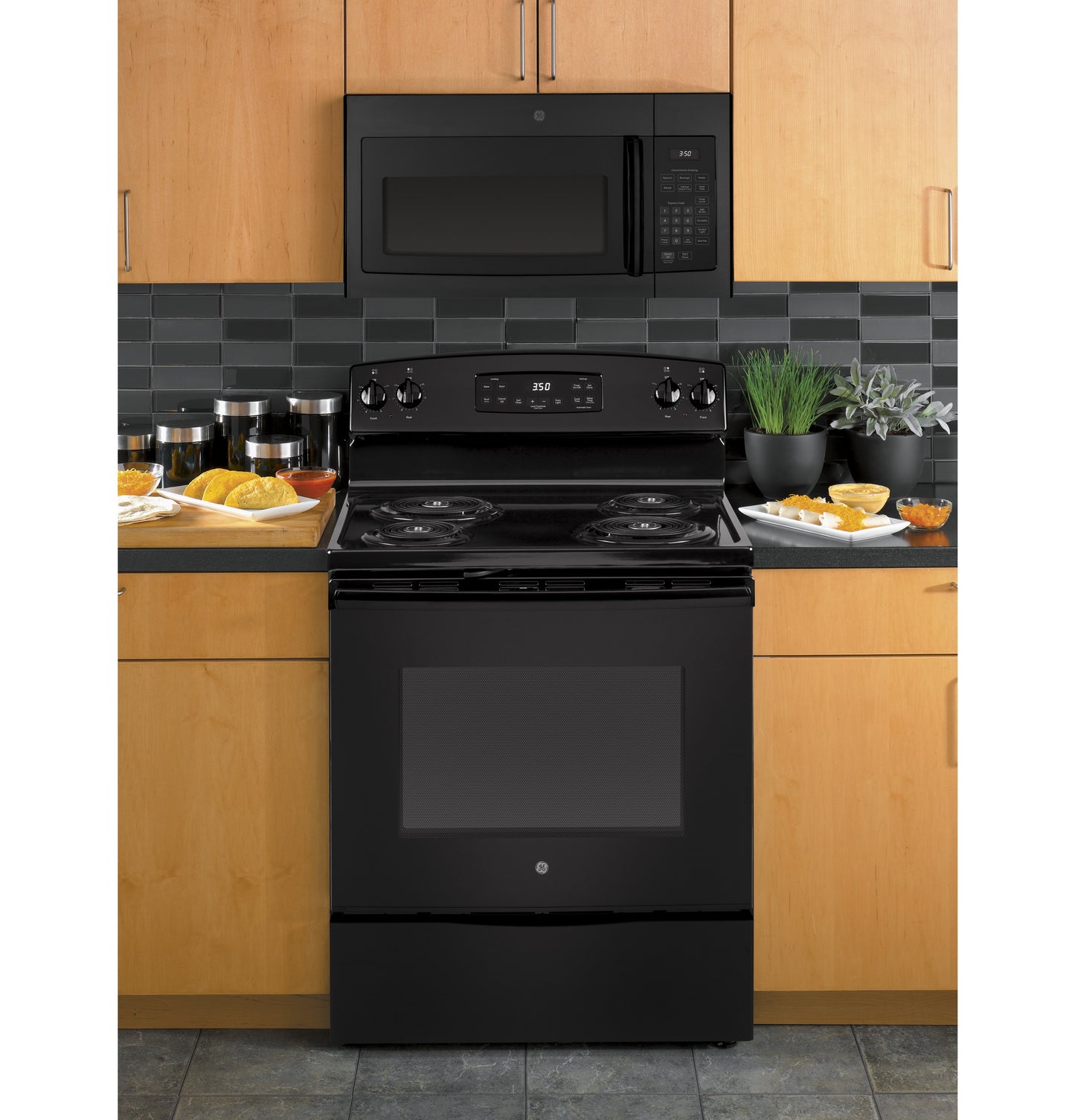 Black over-the-range microwave with digital keypad installed above black electric stove in modern kitchen setting in Microwaves collection