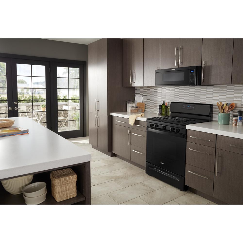 Modern kitchen featuring black low profile microwave hood combination above gas stove with gray cabinetry and white countertops