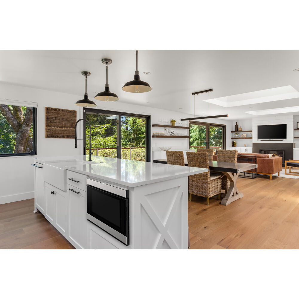 Built-in microwave drawer installed in modern white kitchen island with pendant lights and open living space