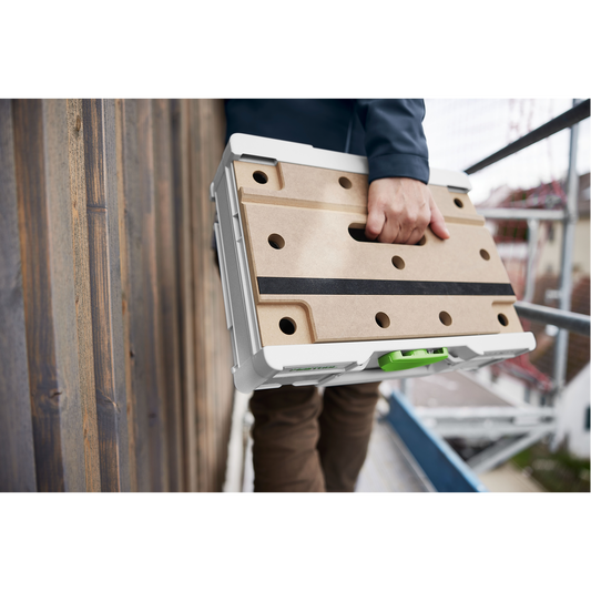 Person carrying a compact Festool modular storage box with a perforated wooden lid and white frame, ideal for workshop organization and tool storage.