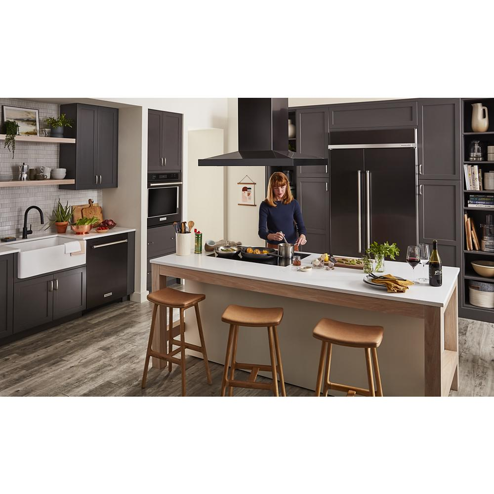 Spacious kitchen with dark cabinetry, large island, stainless steel appliances, and island-mount canopy hood in modern style