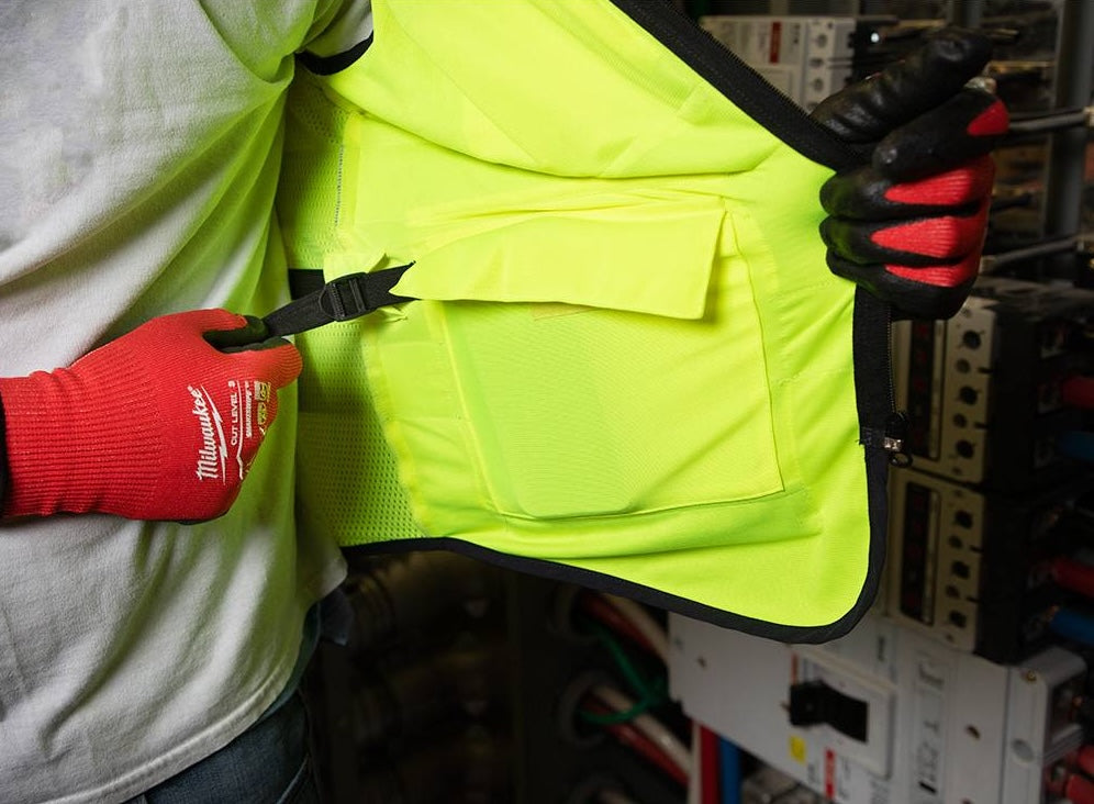 Yellow high visibility performance safety vest with multiple reinforced pockets shown in use with red work gloves in safety gear collection