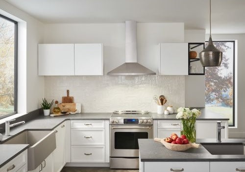 Modern kitchen setup featuring a stainless steel pyramid-style chimney hood above a gas range with white cabinetry and gray countertops