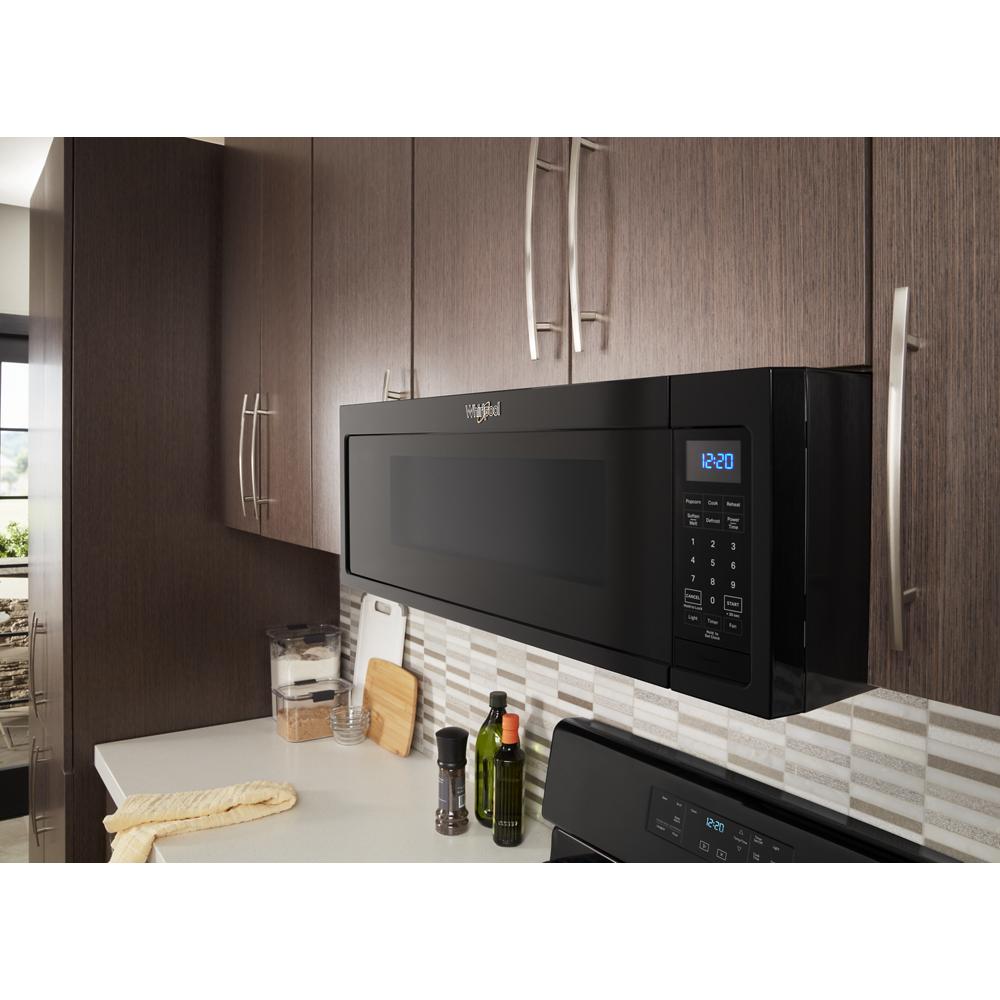 Black low-profile microwave hood combination installed above stove with digital display in kitchen with wood cabinets