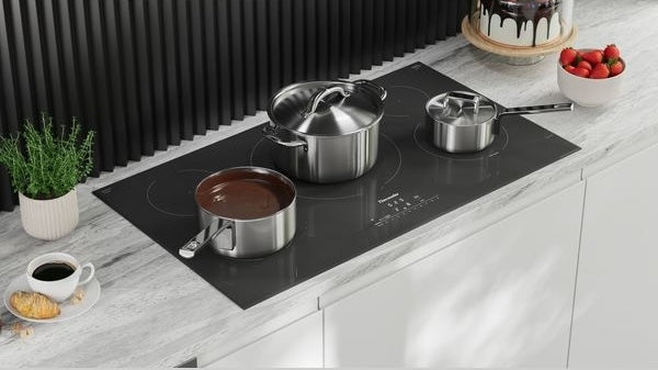 Black 36-inch induction cooktop with three stainless steel pots heating on marble countertop from Thermador Appliances collection