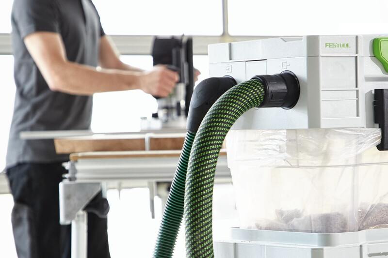 Green anti-static extractor hose with smooth outer skin attached to a dust collector in a woodworking setup