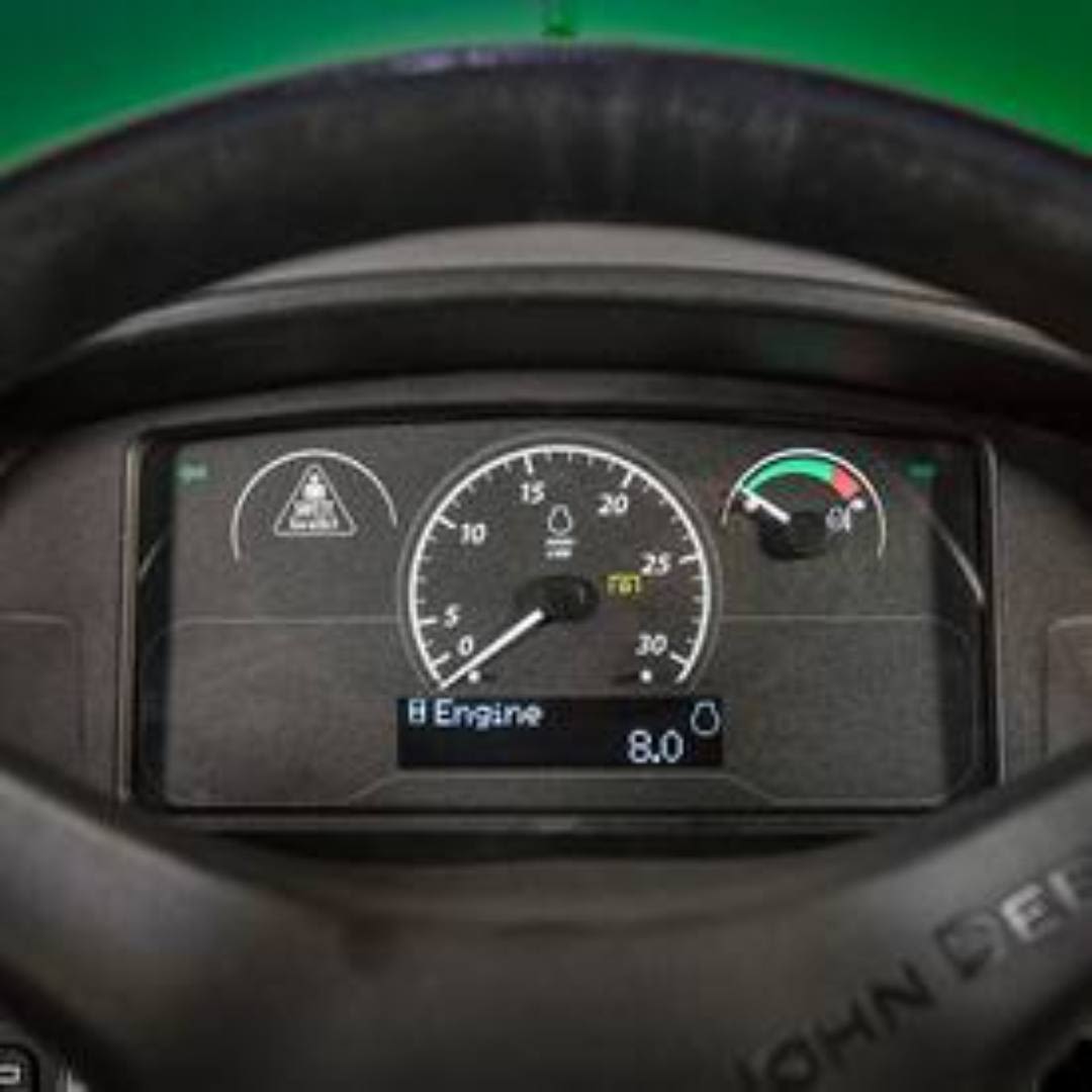Close-up of tractor dashboard showing engine speed, warning indicator, and temperature gauge on utility tractor panel