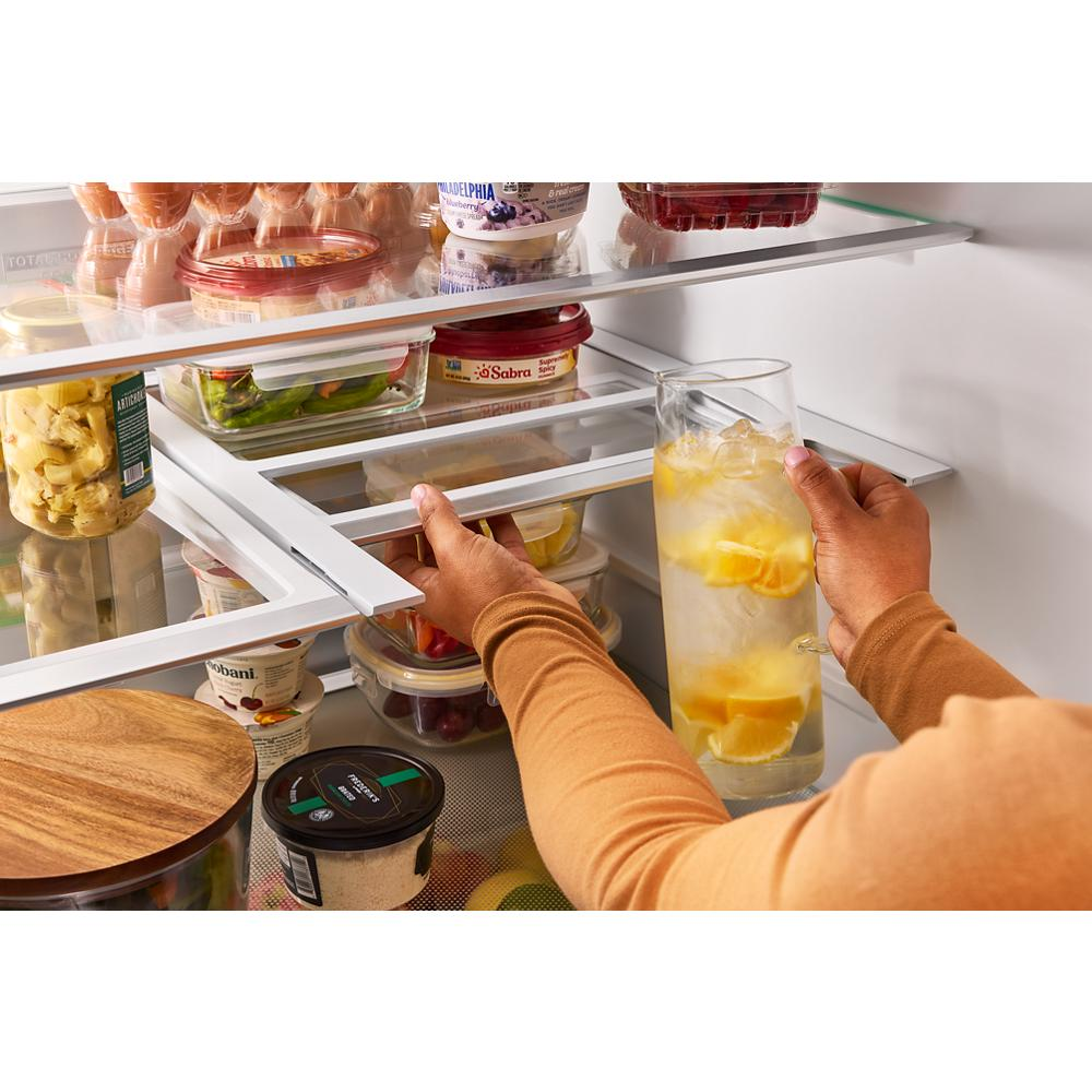 Person reaching into French door refrigerator to grab glass of ice water with lemon in kitchen appliances collection