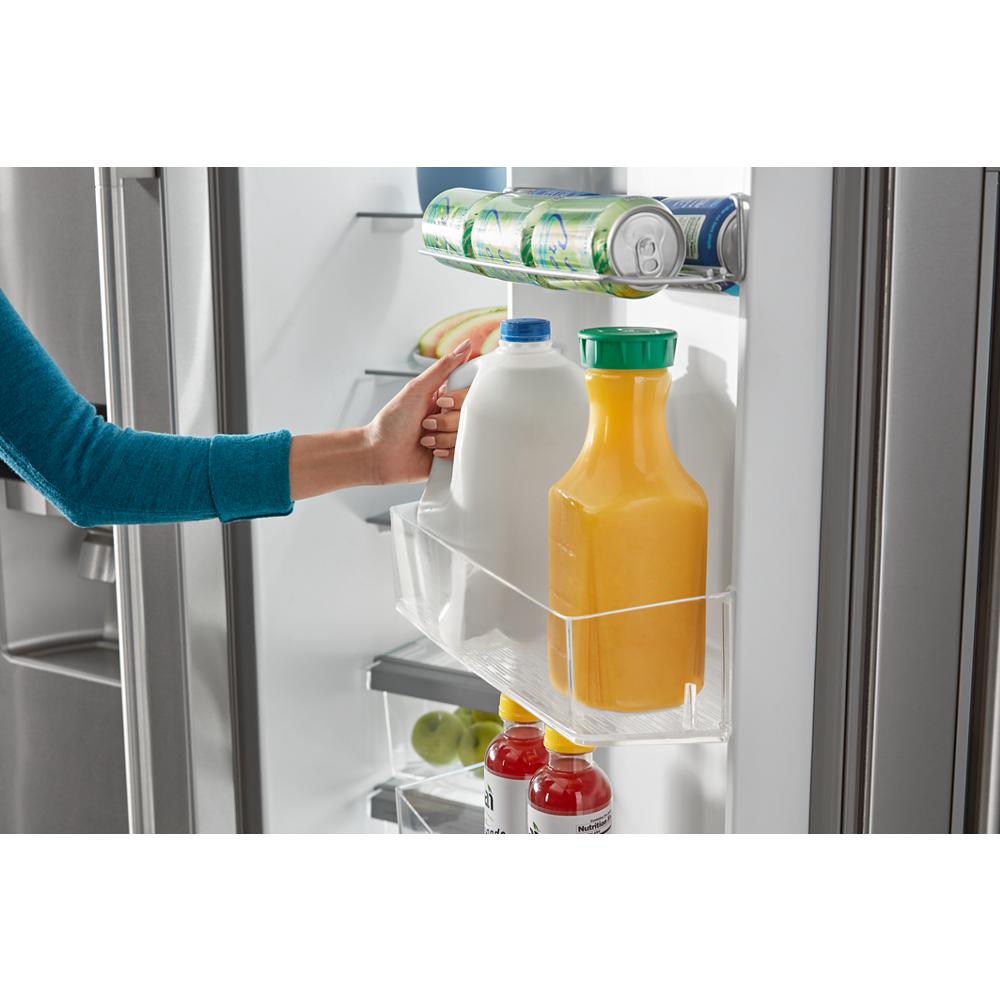 Hand reaching for gallon milk jug beside orange juice and cans stored in door bins of side-by-side refrigerator door