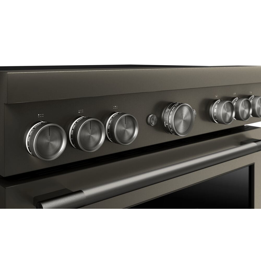 Close-up of black commercial-style range control panel with six brushed metal knobs for cooking and home improvement.