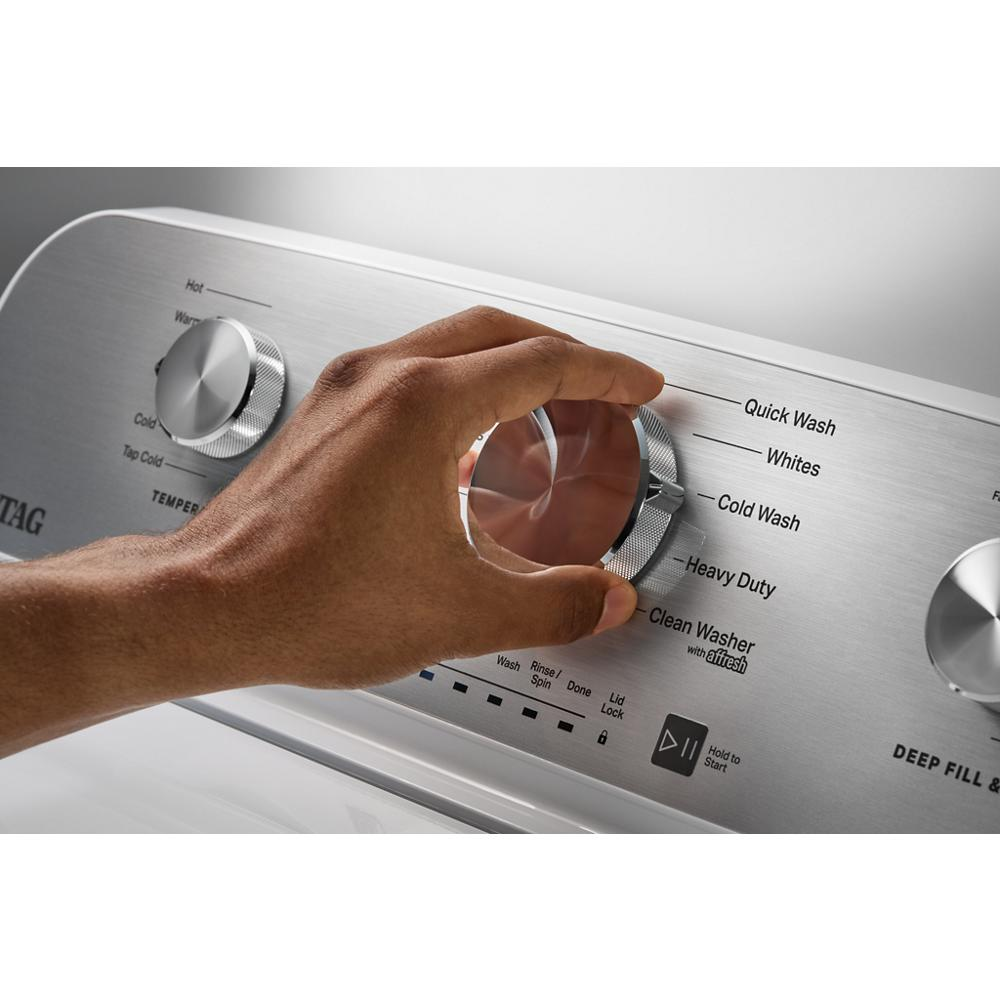 Close-up of hand adjusting stainless steel cycle selector knob on top load washer control panel in washers collection