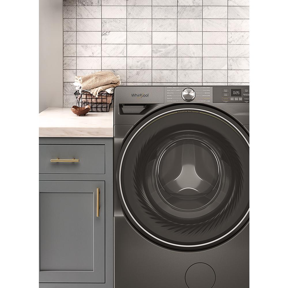 Dark gray front load washer with digital display beside gray cabinet and white countertop in laundry room setting