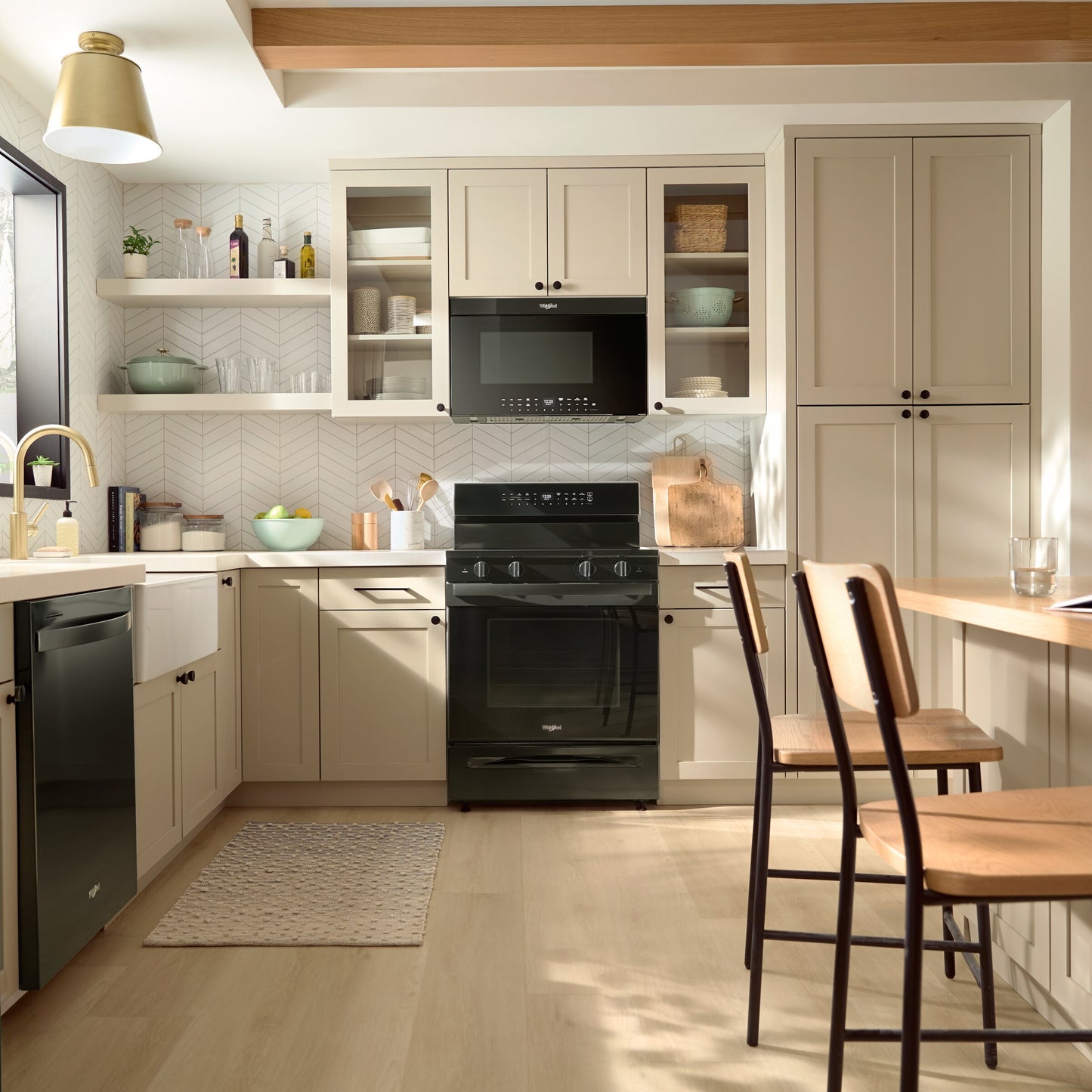 Black air fry microwave built into beige cabinetry above matching oven in modern kitchen with hardwood floor and breakfast seating