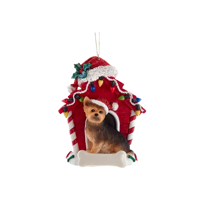 Yorkshire Terrier figurine wearing Santa hat sitting in front of festive red dog house ornament with holiday lights