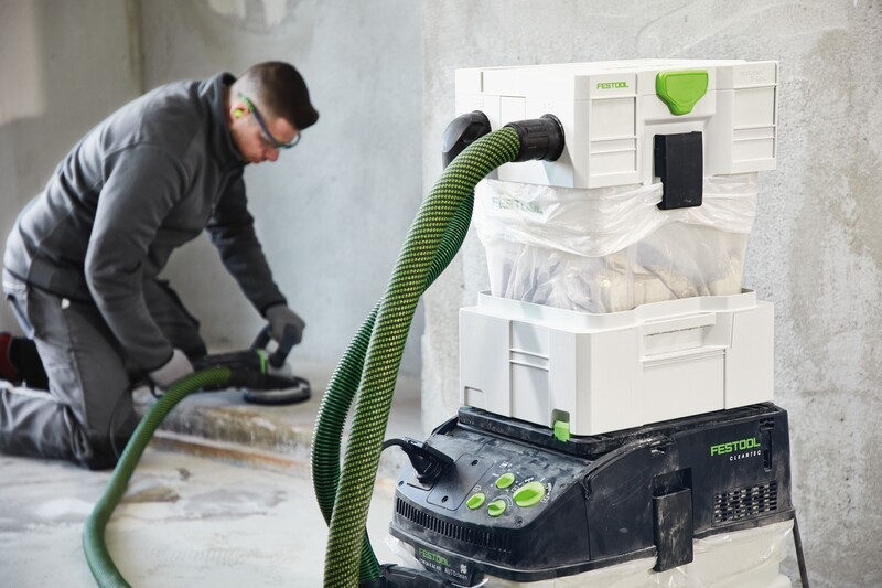 Worker using a Festool dust extractor with disposable liner in woodworking dust collection and air filtration setup